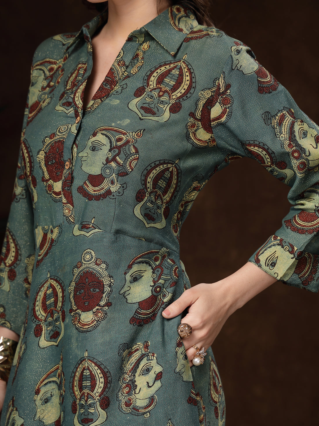 Woman wearing a patterned dress standing in a dark room with a textured floor.