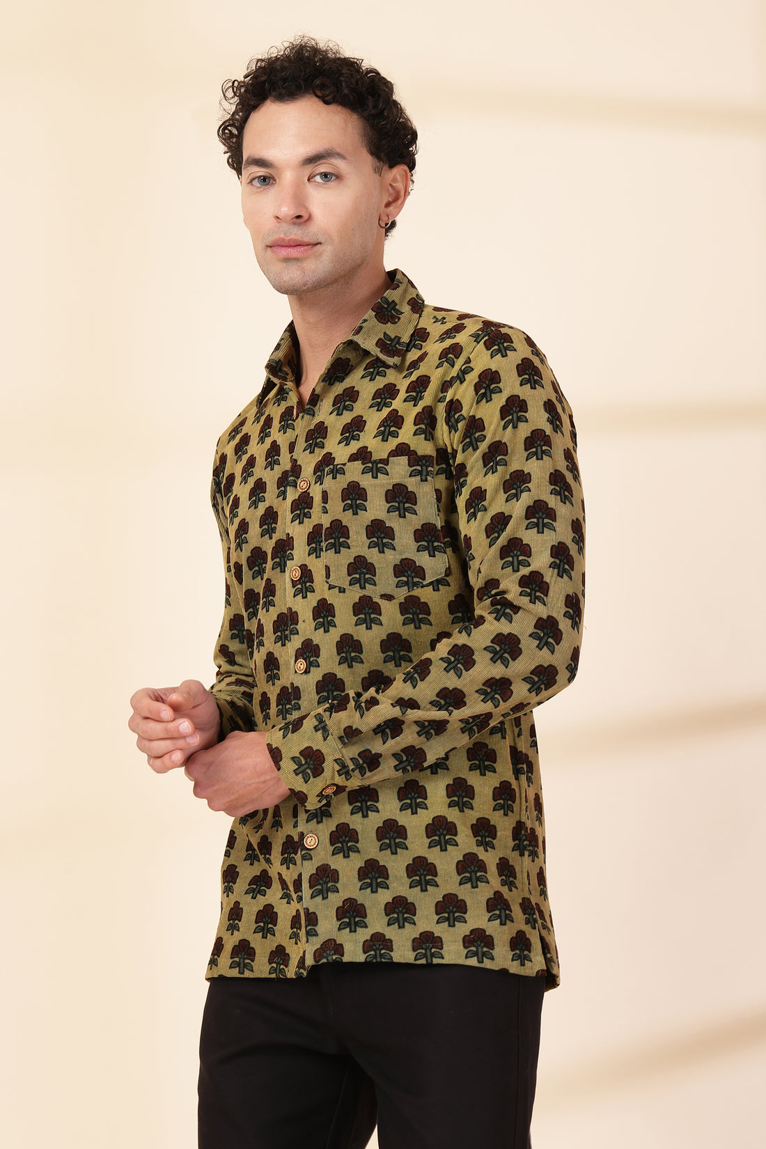 Man wearing a green patterned shirt against a beige background